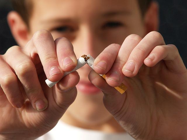 A man breaking a cigarette into half 