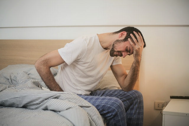 A man sitting on a bed feeling stressed 