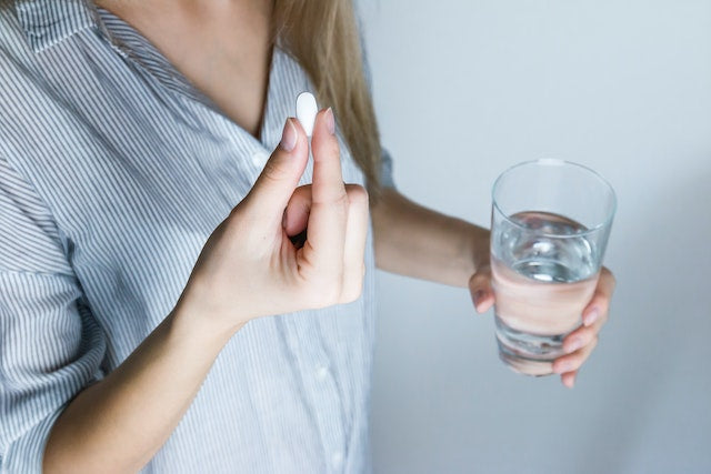 A women taking a pill with glass of water 